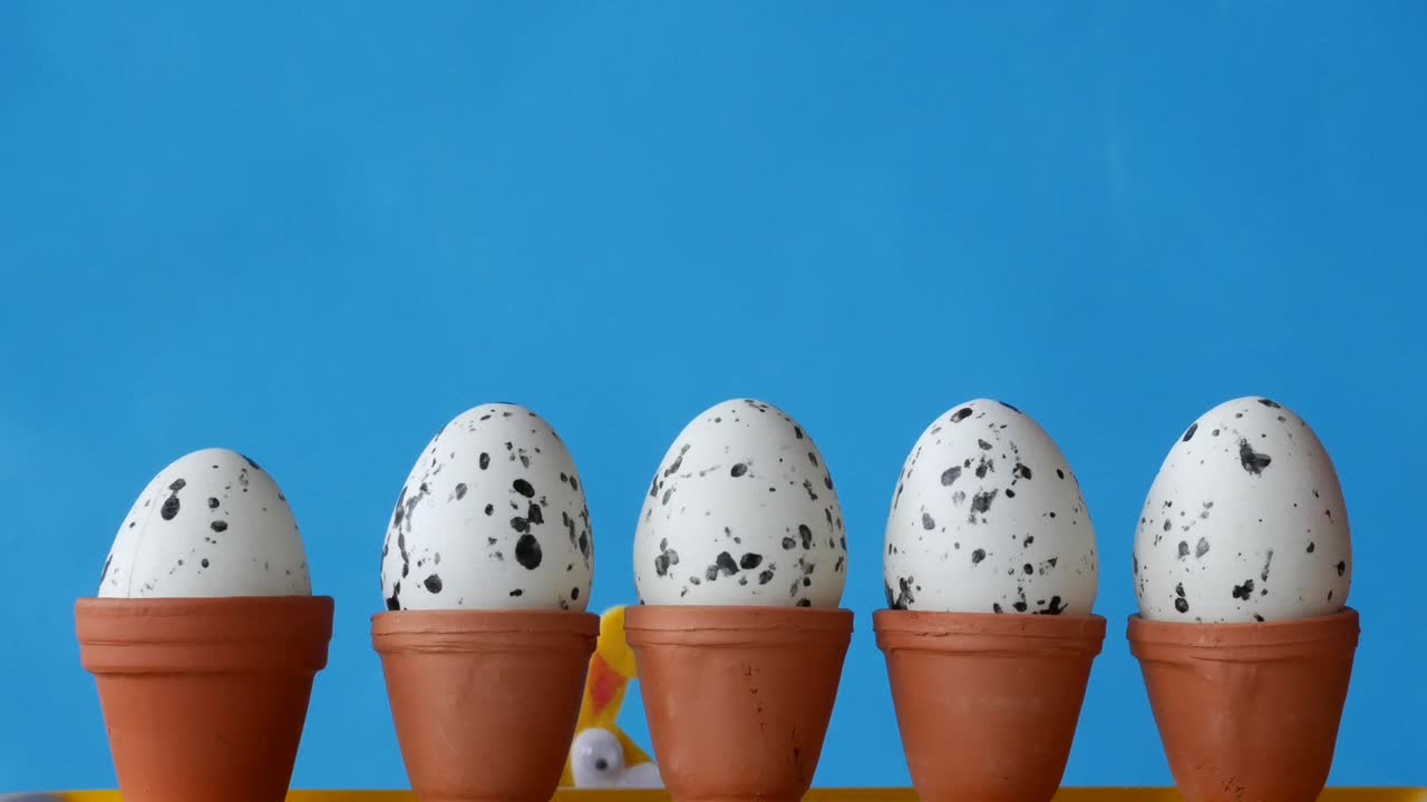 부활절 토끼는 꽃비 뒤에 숨어 있고 알을 낳고 있어요.