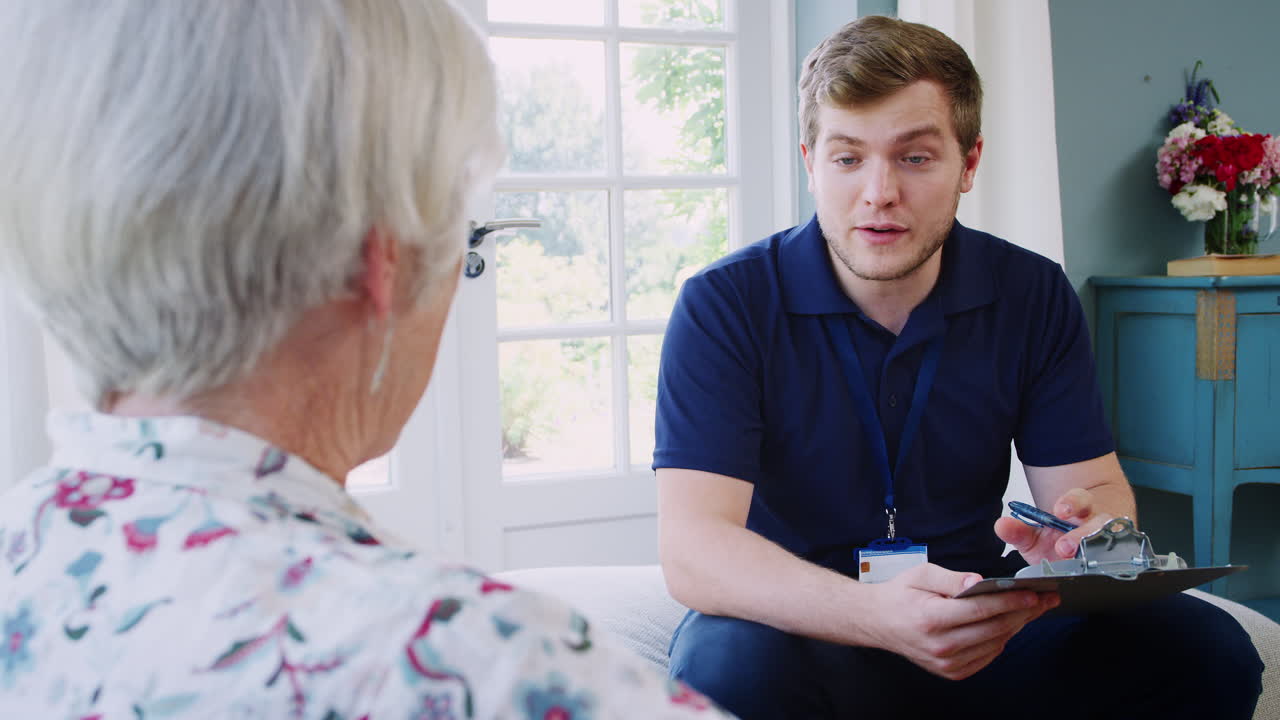 Senior woman talking with male care worker on home visit