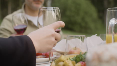 mano de hombre tomando copas de vino de una mesa durante una fiesta al aire libre en el parque