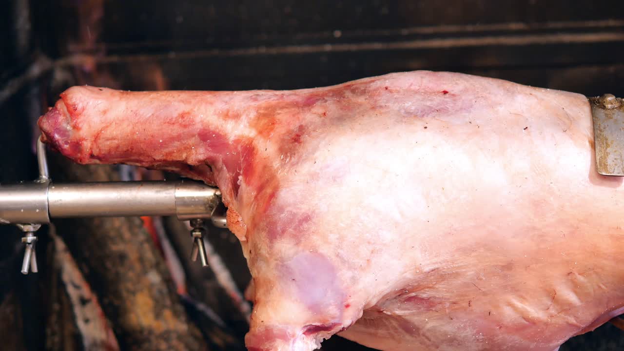primer plano de una pierna de cordero asada en un salto sobre un fuego