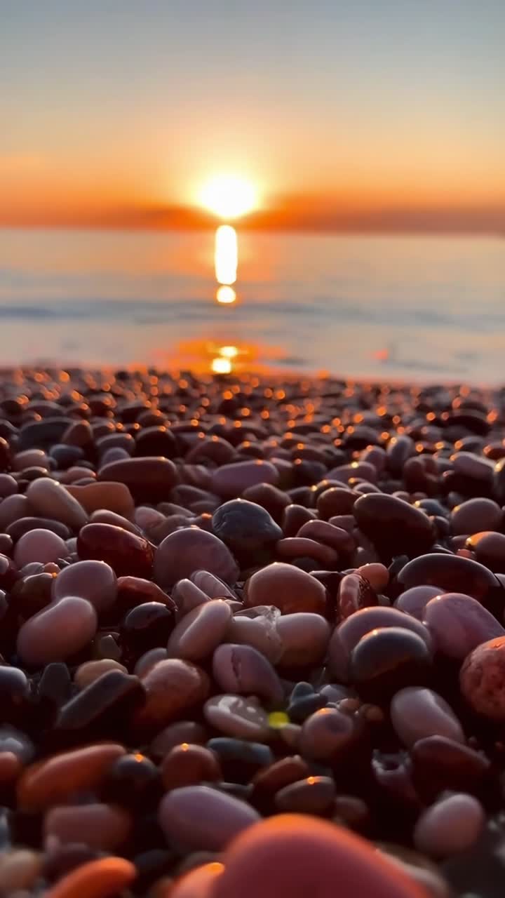 Primo piano di ciottoli sulla spiaggia con tramonto dorato sull'oceano
