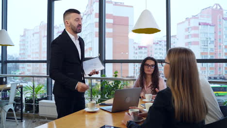 office team drinking coffee and discussing working issues. collaboration and teamwork in a cozy office with panoramic windows.