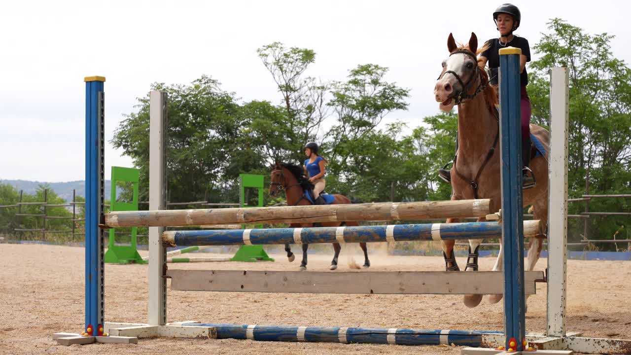 Horse riders training by jumping over obstacles at an equestrian center