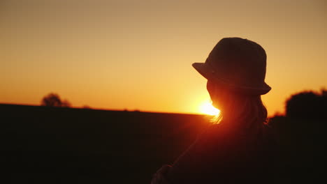 una mujer con sombrero espera la esperanza de la puesta del sol y el concepto de futuro brillante video en cámara lenta de 4k