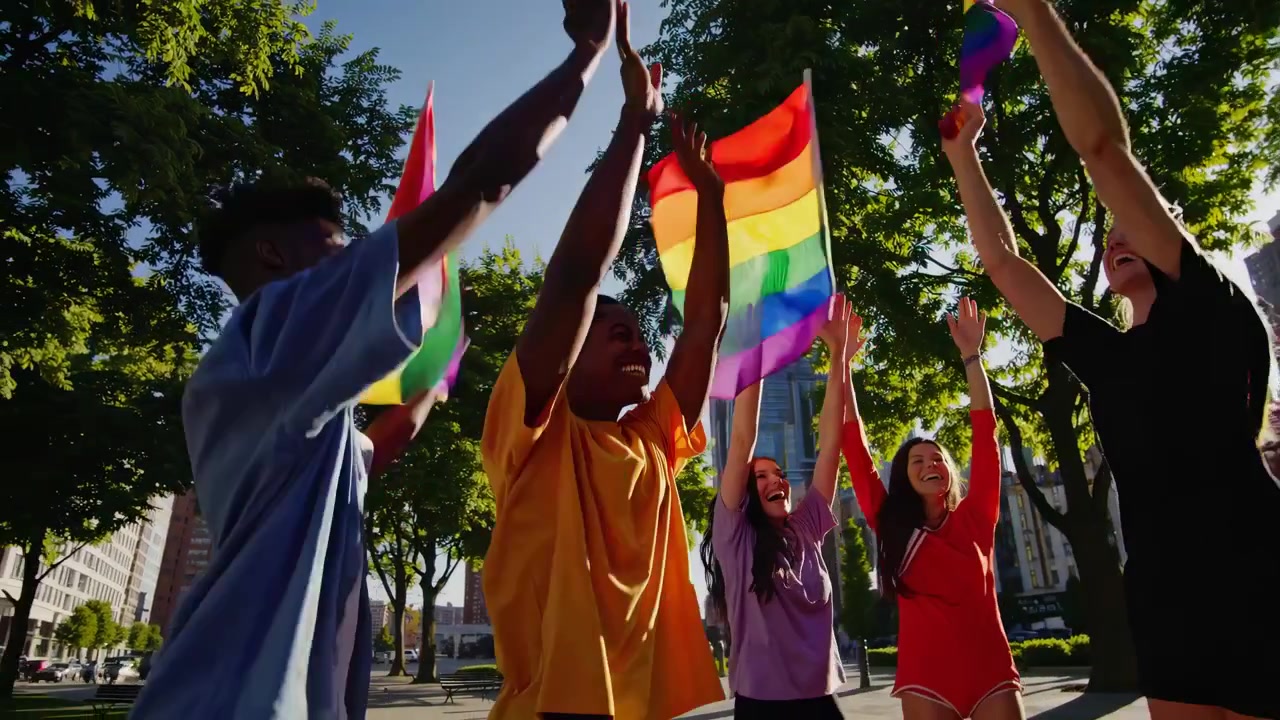 Diverse Group of Friends Celebrating with Pride Flags in City Park