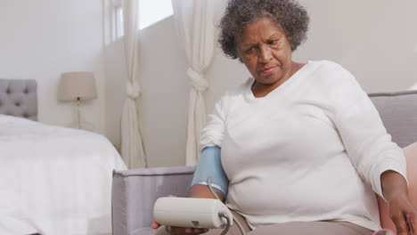 mixed race woman checking her blood pressure. social distancing and self isolation in quarantine