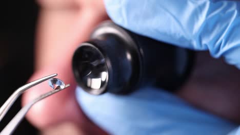 gloved technician holds magnifying glass and tweezers and looks at gem 4k movie