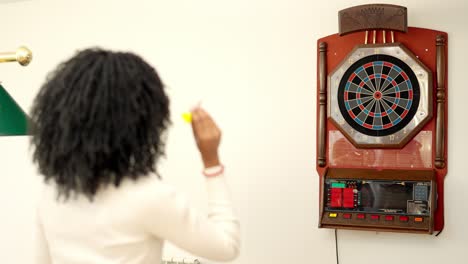 rear view of an african woman playing darts at home