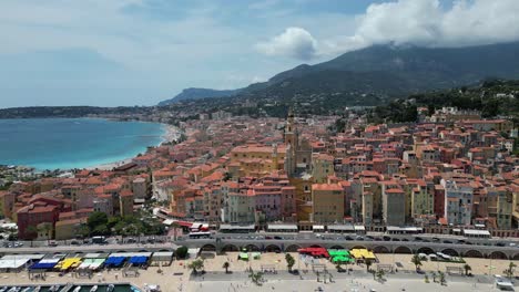 Plage-des-Sablettes-beach-in-Menton-France-and-old-town-with-Saint-Michel-Basilica,-Aerial-approach-shot