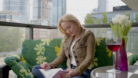 blond woman reading diary on terrace