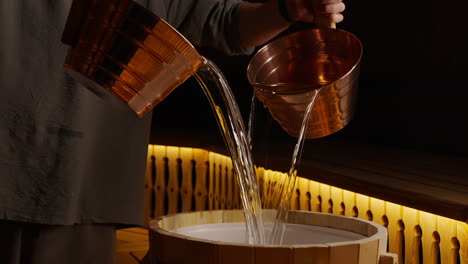 pouring water into a sauna barrel