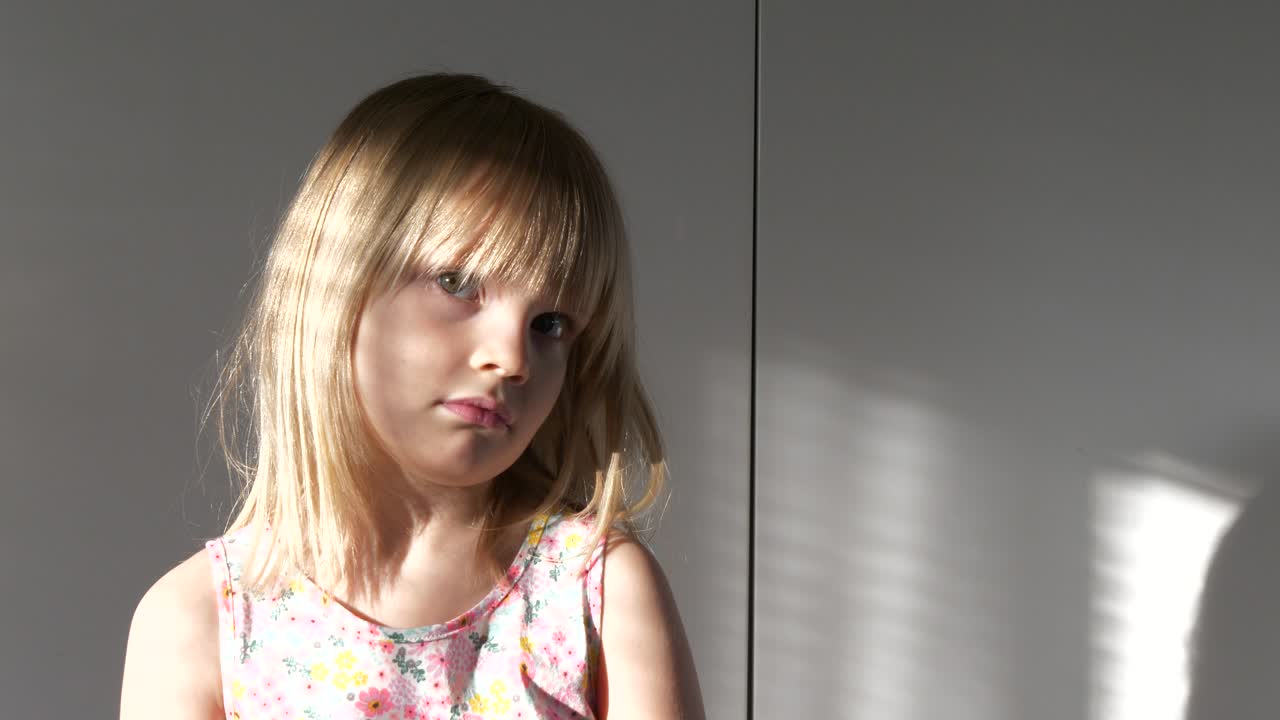 linda chica caucásica rubia, mirando a la cámara, neutral, rayo de sol desde la ventana, plano medio