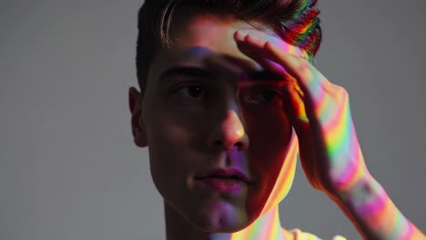 young man bathed in colorful rainbow light