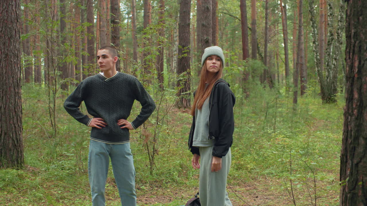 Colleagues stand quietly among tall trees in tranquil forest, observing surroundings with thoughtful expressions and relaxed postures, during calm woodland exploration