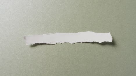 video of close up of torn piece of white paper on green background