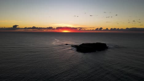 a marine park island rising above the ocean contrasted against an early morning colorful sunrise