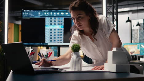 woman real estate engineer reviews city planning blueprints on laptop