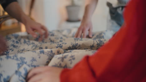 male and female friends putting tablecloth on table