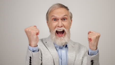 cheerful man posing to camera in studio. aged guy celebrating victory indoors.