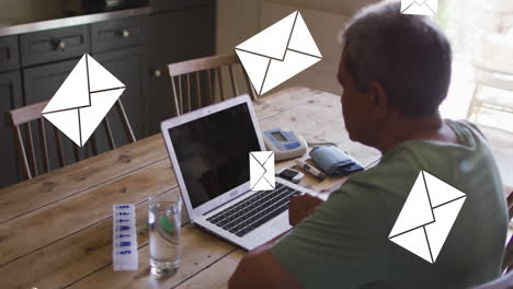 animation of envelope icons over senior man using laptop at home in background