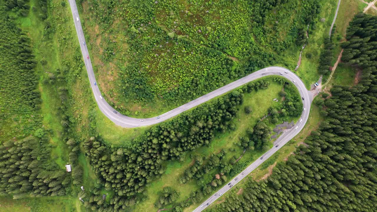 zoom aéreo en la vista de arriba hacia abajo del dron de los automóviles que circulan por una hermosa carretera curva en las montañas del parque nacional de los bajos tatras en eslovaquia