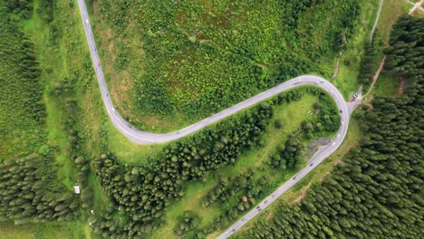 aerial zoom in drone top down view of cars driving on a beautiful s curved road in the mountains of low tatras national park in slovakia