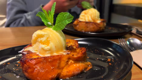 Dos-Sabrosas-Tostadas-Francesas-Pain-Perdu-Con-Helado-De-Vainilla-Y-Hojas-De-Menta-Fresca-En-Un-Plato,-Postre-Dulce-En-Un-Restaurante,-Toma-De-4k