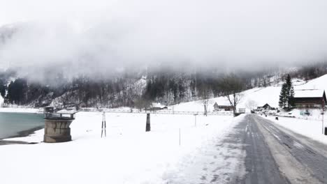 view of a frozen klontalerstrasse lake with low clouds during the winter season in glarus, switzerland