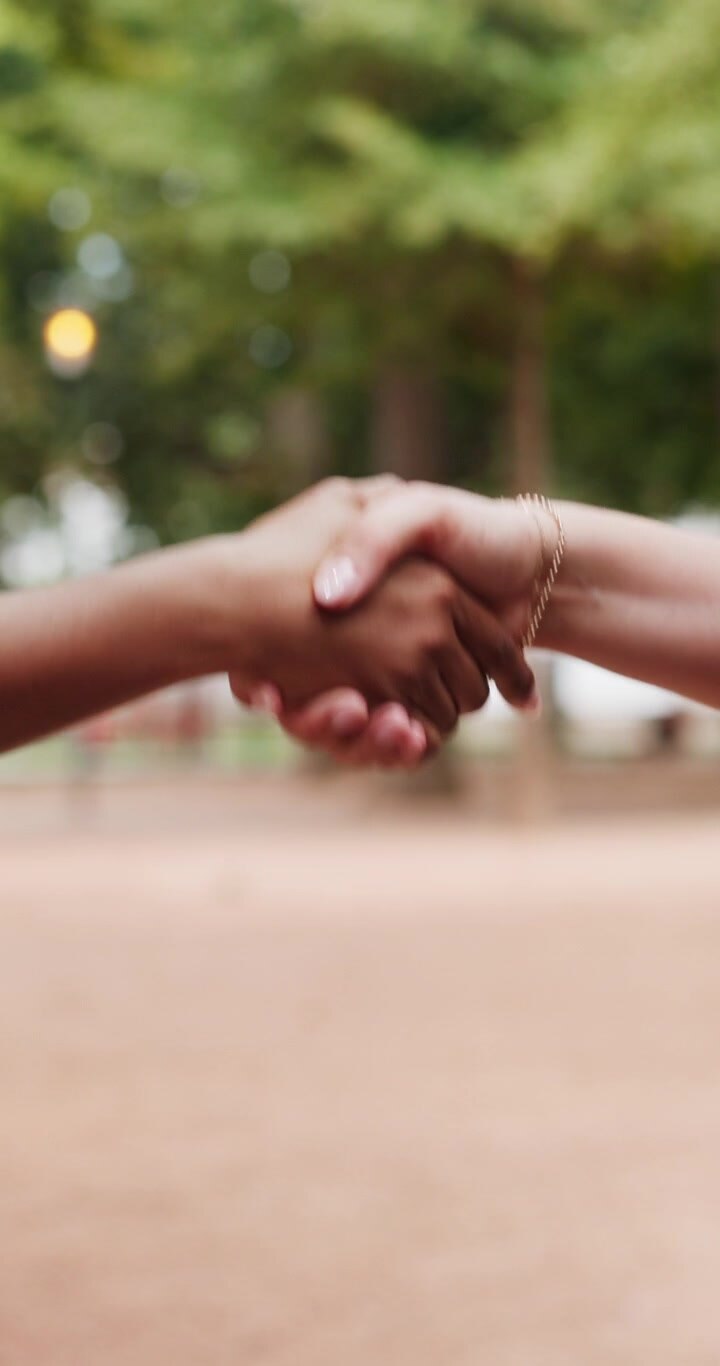 Two People Shaking Hands in a Park