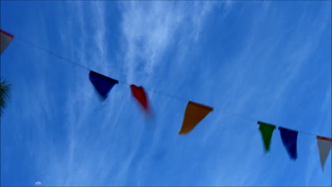 video shot of colorful flaglets blown by wind and a blue sky