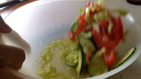 echando verduras mixtas en un recipiente de plástico mezclándolo con aceite de oliva