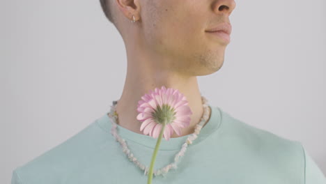 handsome man with green t shirt and necklace holding flower