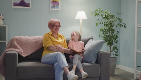 Una-Niña-Bonita-Se-Ríe-Leyendo-Un-Libro-Con-Sus-Abuelos