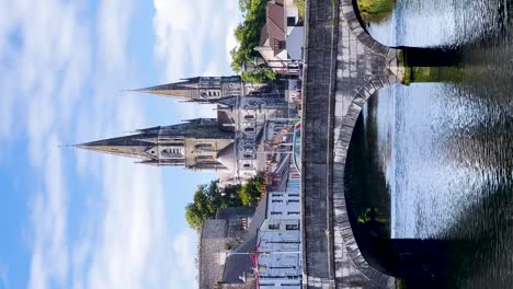 Paisaje-Urbano-Soleado-De-Cork:-Vídeo-Vertical-Del-Puente-South-Gate-Sobre-El-Río-Lee-Con-La-Catedral-De-Saint-Fin-Barres-Al-Fondo