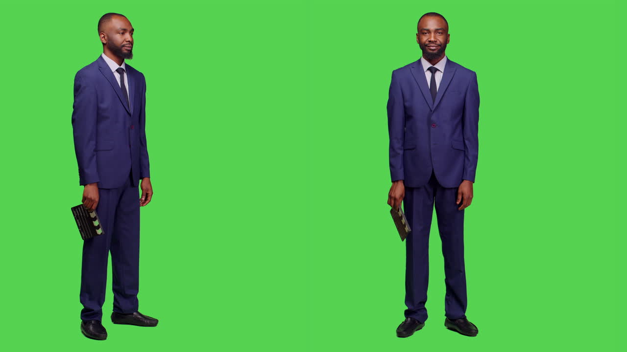 Man in suit holding clapperboard in front of green screen