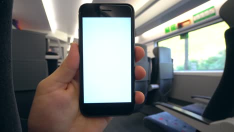 una mano sosteniendo un teléfono con una pantalla blanca en el tren