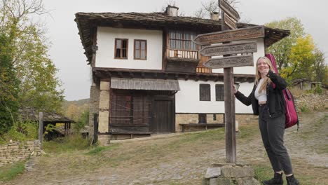 happy female musician gives thumbs up village direction signpost