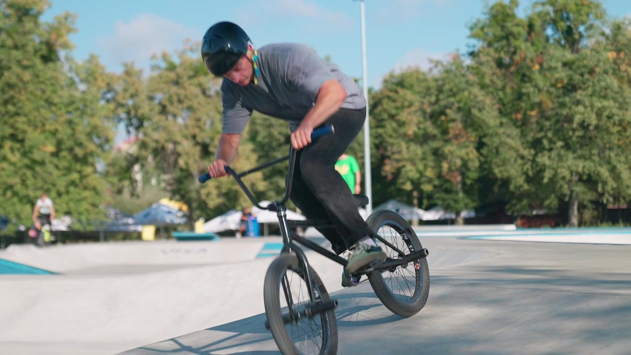 Abile rider BMX che esegue un trick manual in uno skatepark all'aperto.