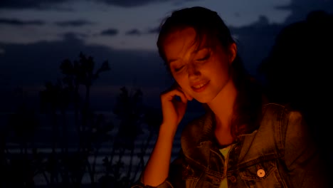 young caucasian girl sitting by the fire in the nature, and looking at the camera, portrait