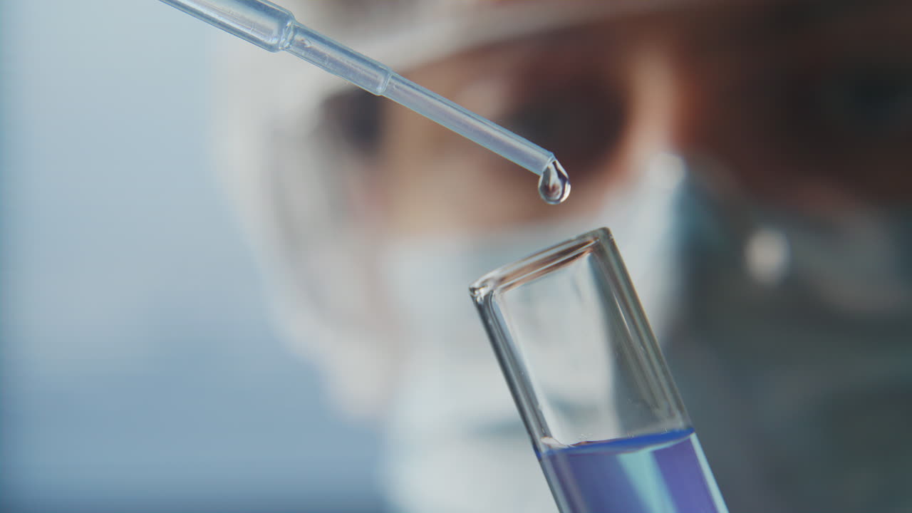 Close Up of Lab Technician Dispensing Liquid from Pipette into Test Tube