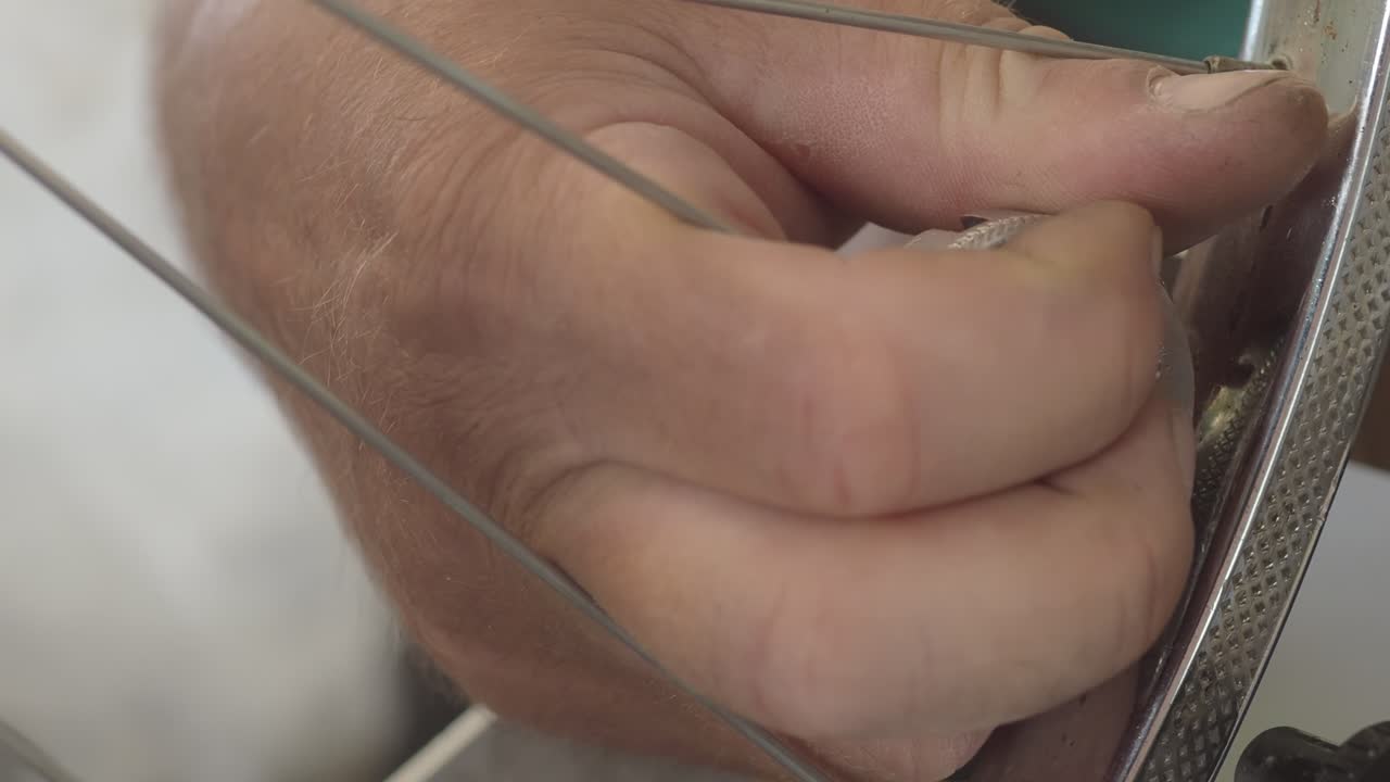 Close up of unrecognizable bicycle mechanic's hands working on a wheel rim, adjusting and repairing it with precision and expertise in a professional workshop, real time