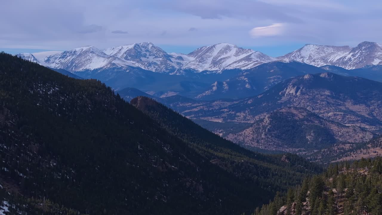 Sentiero di montagna fiancheggiato da alberi e chiazze di neve che attraversa un terreno boschivo elevato, Allenspark, Colorado, USA.
