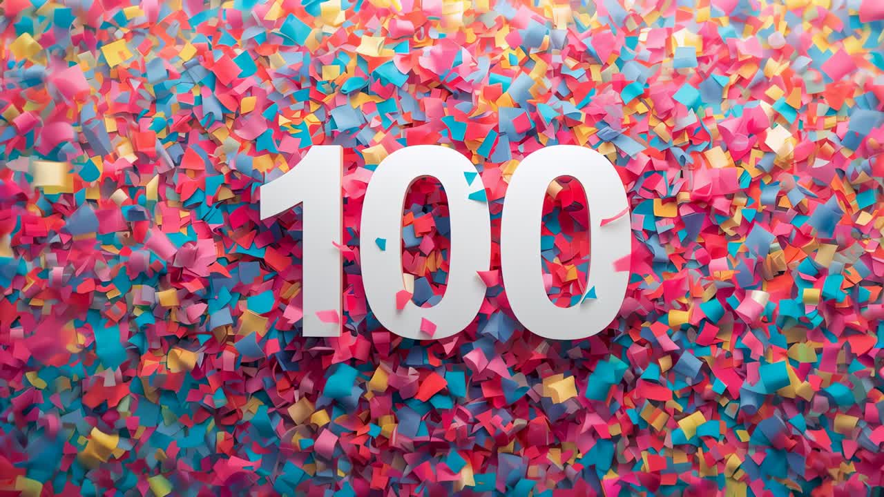 Panning camera revealing large white numeral 100 on confetti bed, confetti shifting