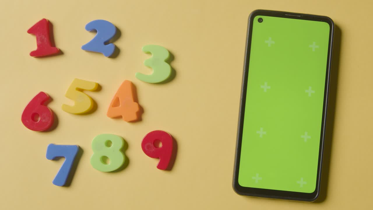 노란색 배경에 녹색 화면 휴대 전화로 순서대로 배열 된 플라스틱 숫자의 스튜디오 오버헤드  ⁇  1