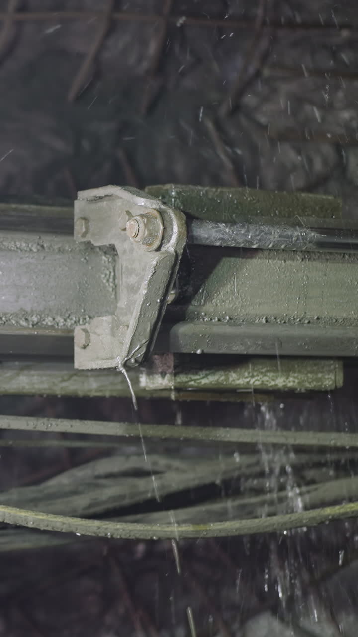 Robot drill does rock drilling in mine spraying cold water. Professional machinery equipment with pipes and coolant makes holes for explosives closeup