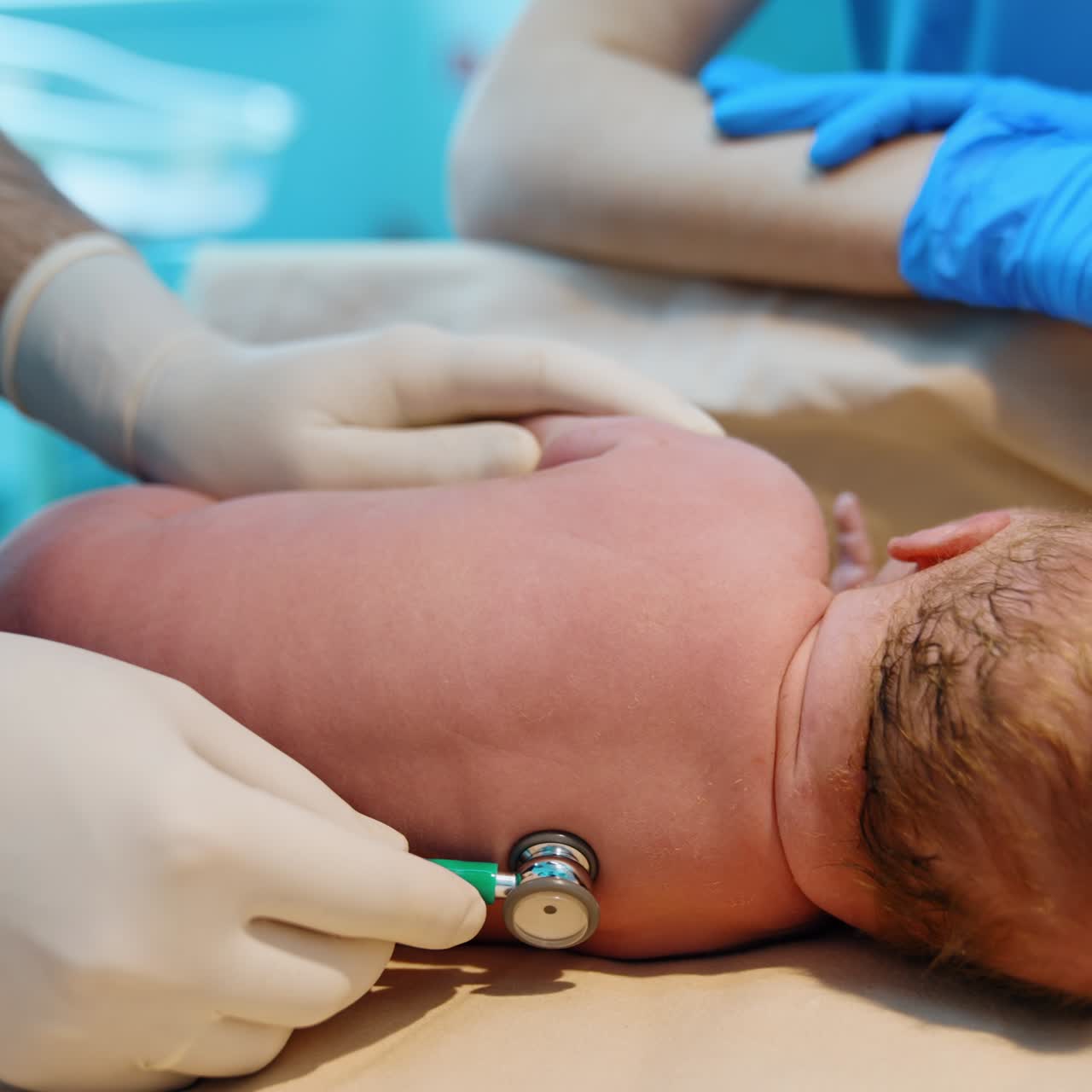 Caucasian newborn is put on its side. Pediatrician listens to baby's heart and lungs after birth. Close up