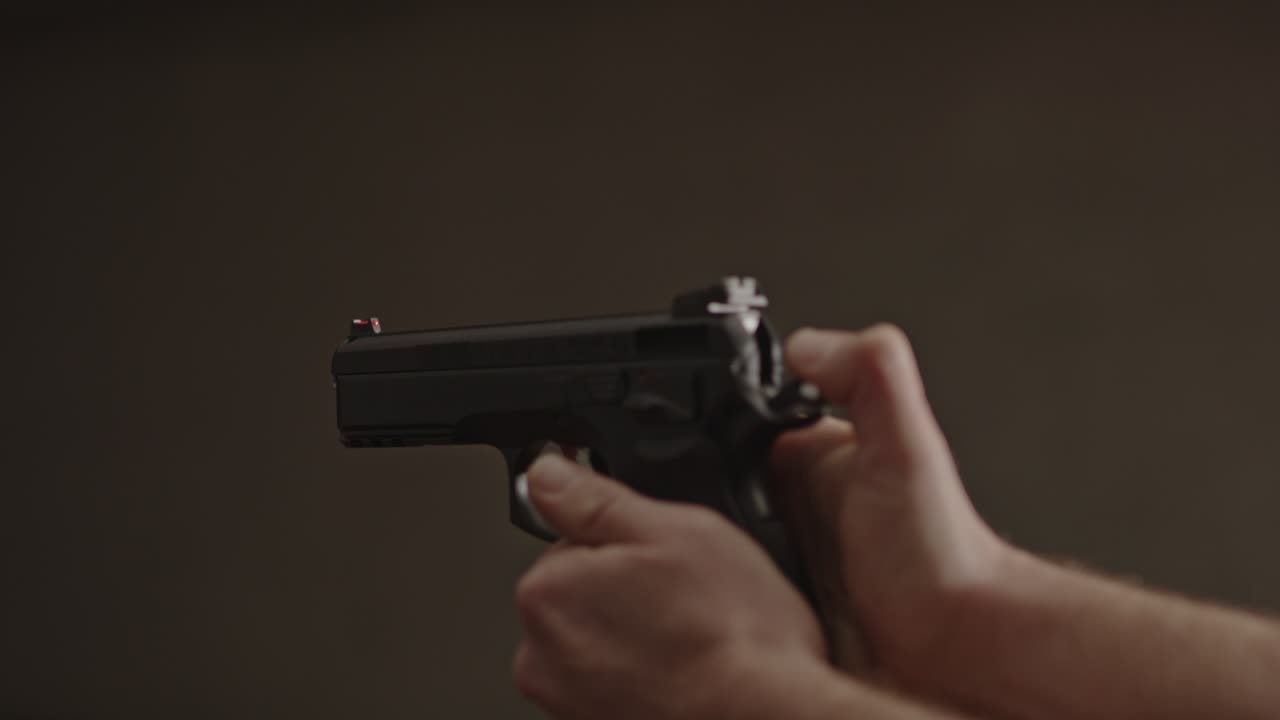 pulgar tirando hacia atrás el martillo de la pistola y disparando