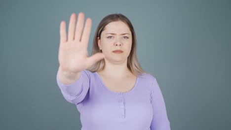 mujer joven haciendo una señal de alto para la cámara.