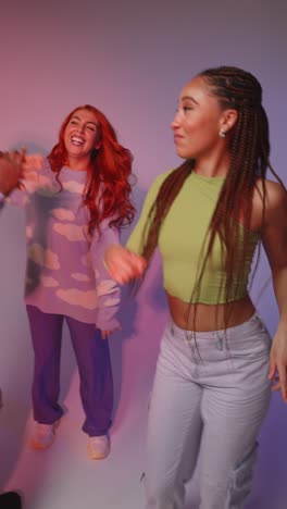 vertical video studio shot of vertical video of group of gen z friends dancing and having fun against pink background 3