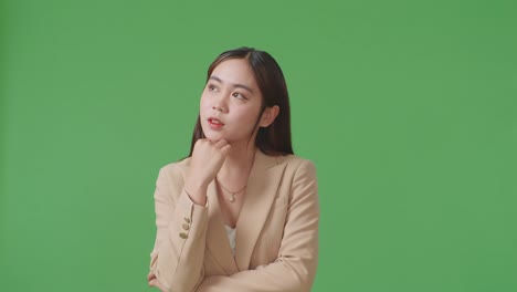 an asian business woman thinking about something and looking around on green screen in the studio